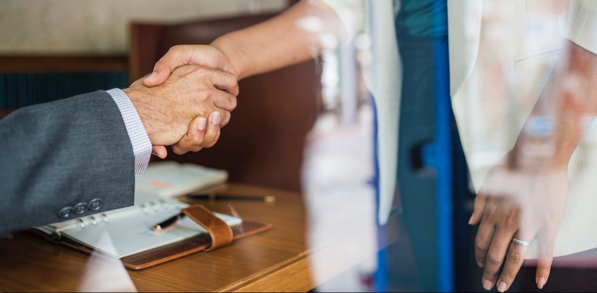 A manager shakes the hand of an employee after explaining the benefits of career outplacement they will receive.