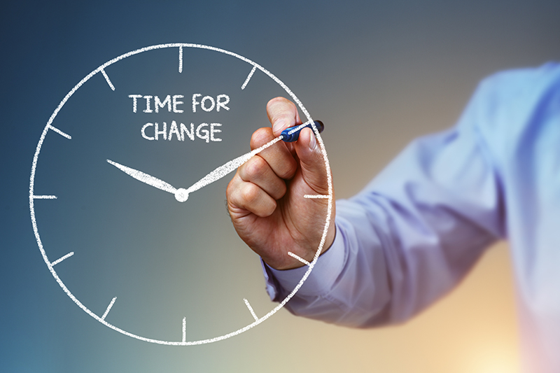 The need for managing organizational change is represented by a businessman drawing a clock that says "time for change"