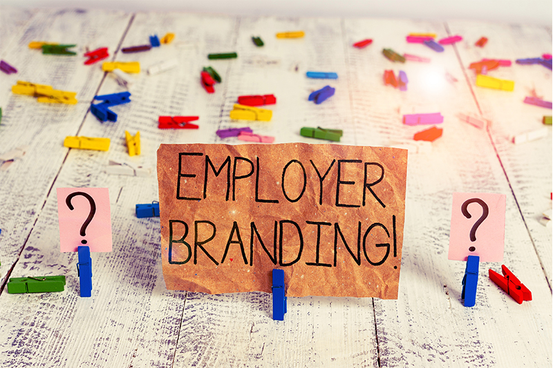 A clothespin holds up a sign that says "EMPLOYER BRANDING!" and on either side of it is a clothespin holding up a question mark, representing wondering how to create a strong employer brand.