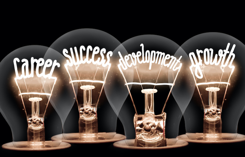 Four lightbulbs glow with the words career, success, development, and growth