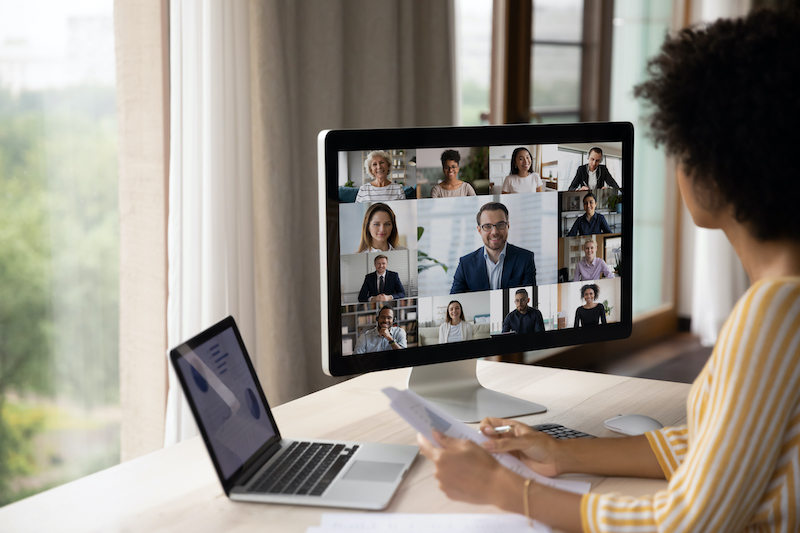 One way to help remote employees feel connected is to schedule frequent all-staff meetings, like the one this woman is attending from her home office.