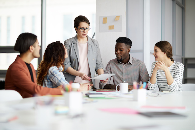 A manager meets with a group of interns to go over a project.