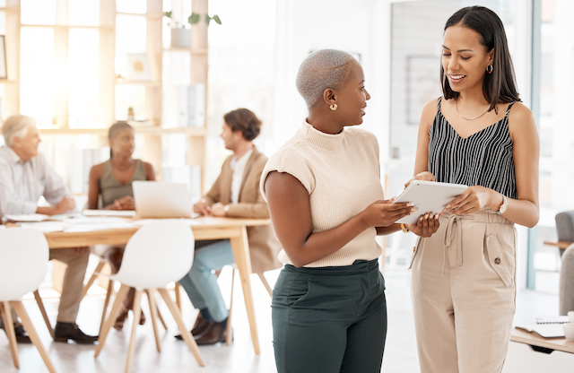 A young Black female leader gets feedback from a female colleague