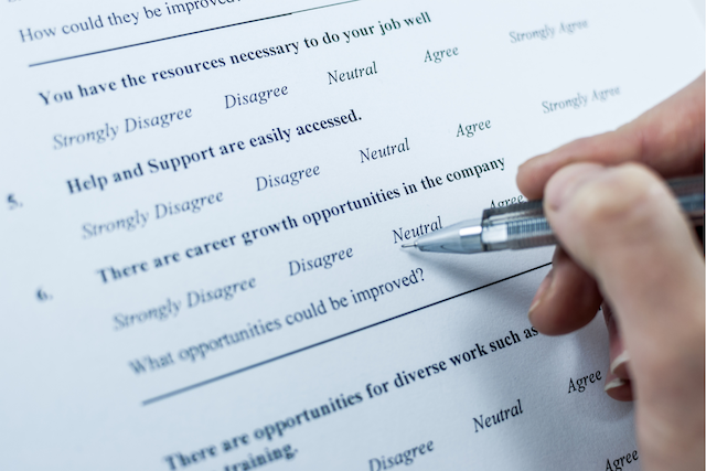 An employee uses a pen to answer questions on a survey from his employer.