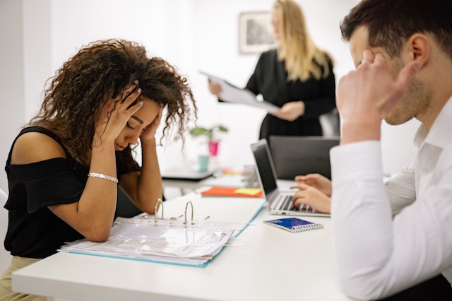 When asking is outplacement worth it, recognize that your remaining employees may experience higher levels of stress - like this man and woman at a meeting - if you don't offer the benefit to their impacted colleagues.