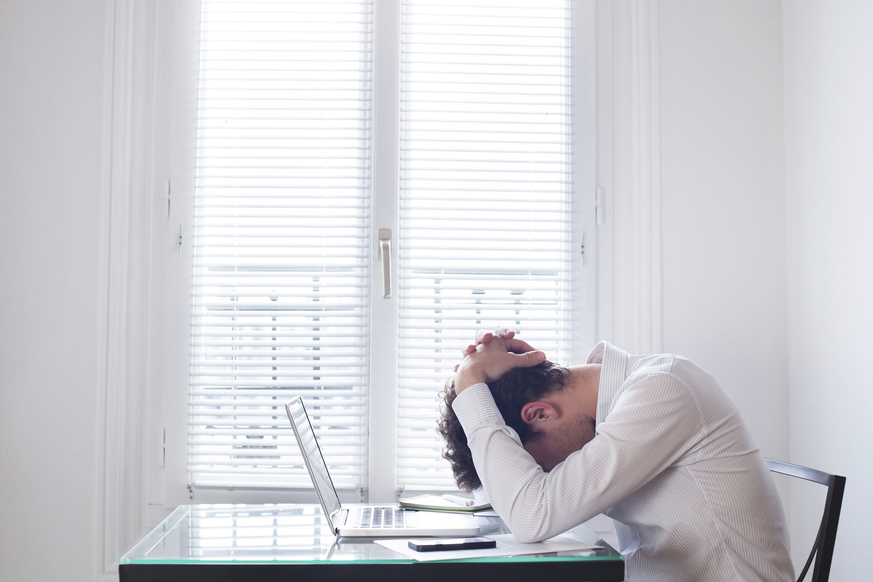 Man at computer with head in hands