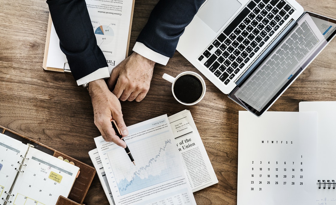 Business man reading financial market information next to PC and coffee