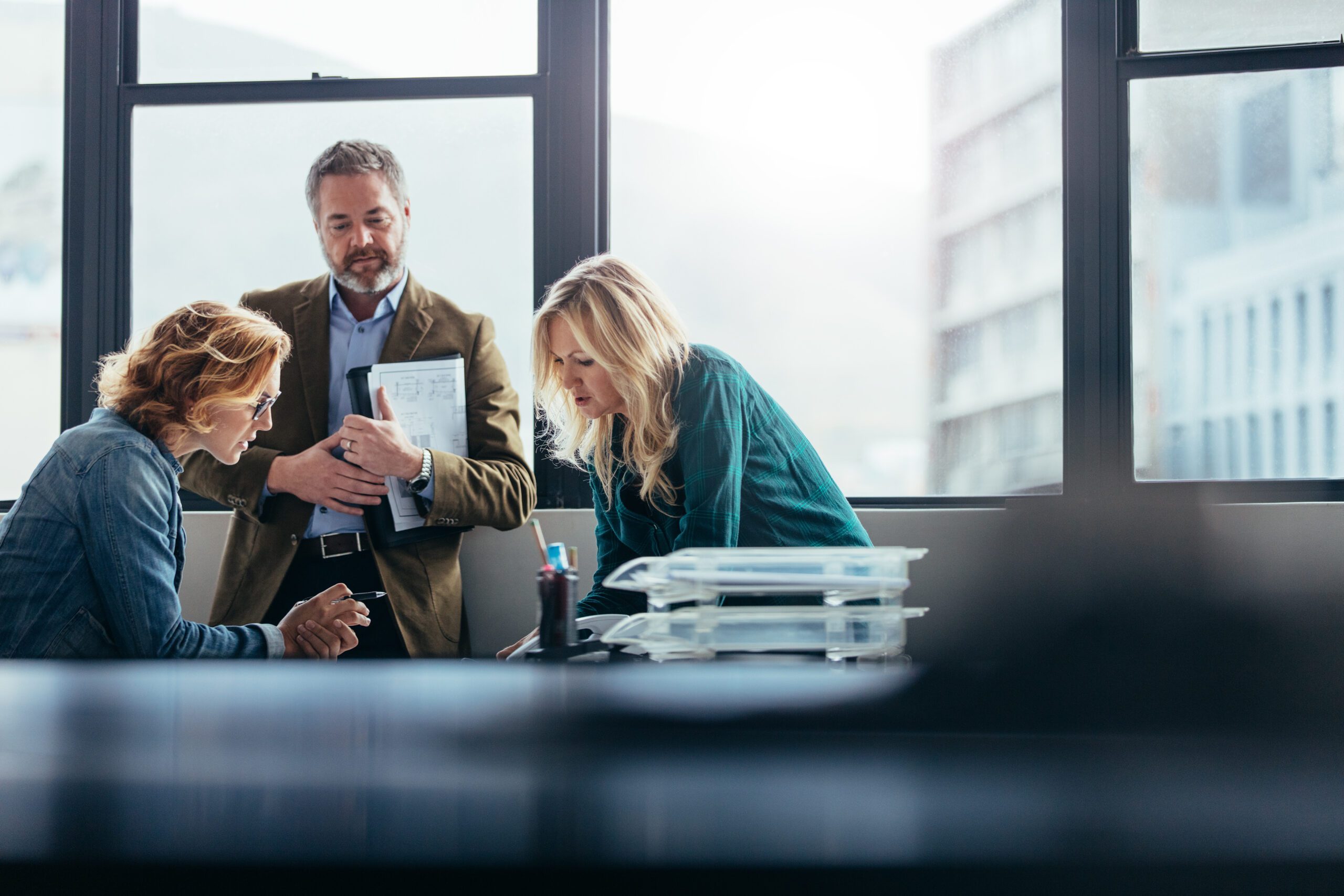 Three employees in office discussing talent shortage