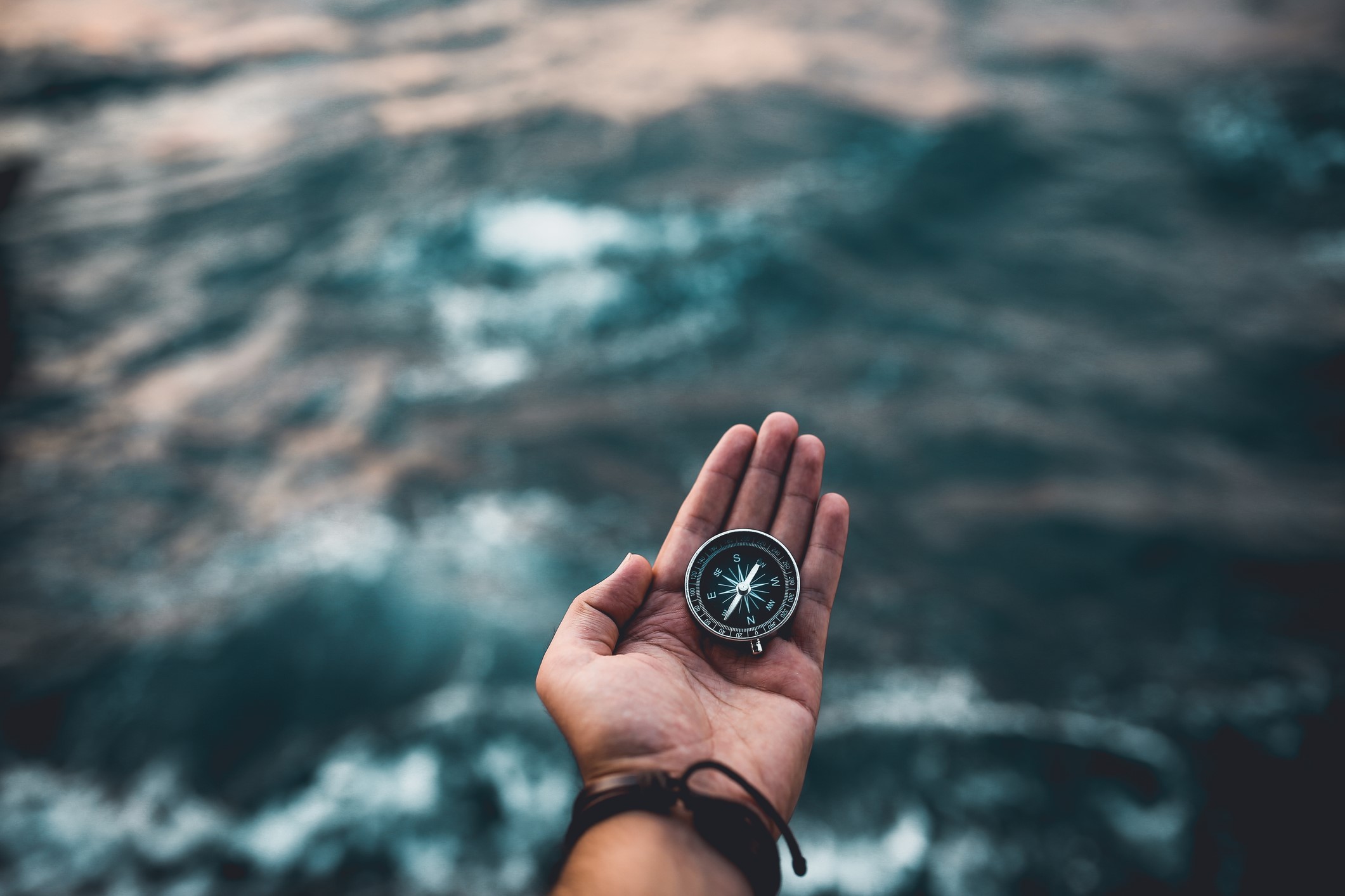 A hand holds a compass in its palm