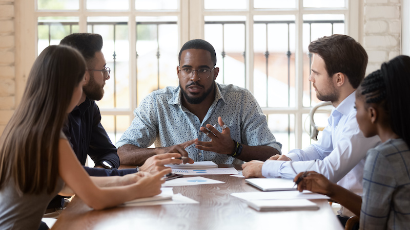 A young Black woman leads her team in a project meeting