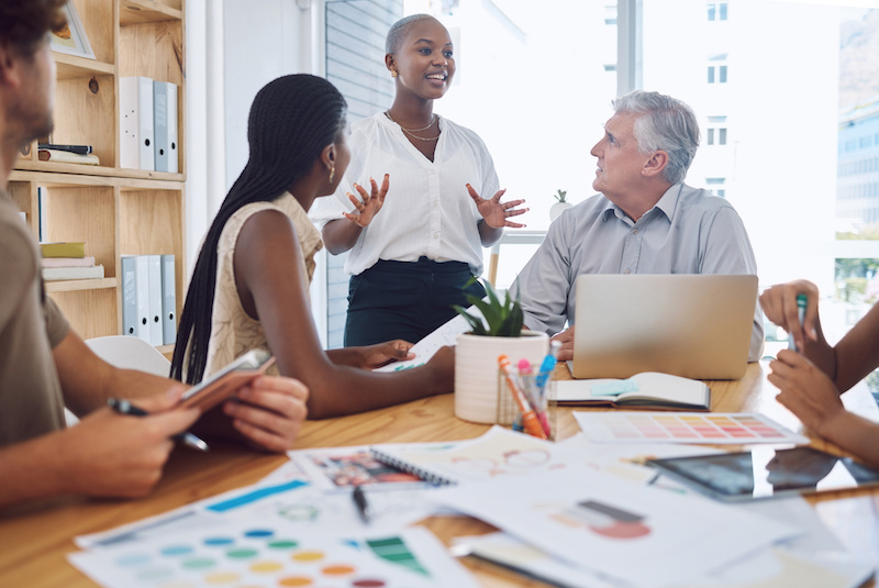 A young Black woman leads her team in a project meeting