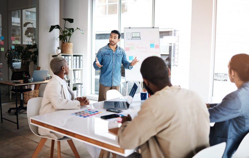 A young Black woman leads her team in a project meeting