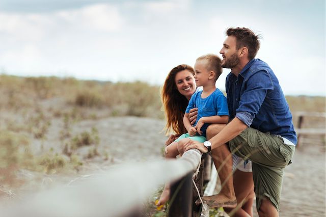 A man takes time off from work to spend time with his wife and son at the beach.