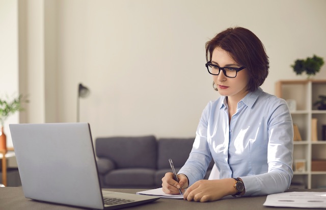 An HR professional takes notes while holding a remote exit interview.