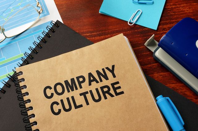 A manual labeled "Company Culture" sits on a desk with papers and office supplies