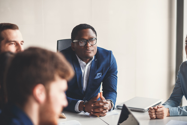 A Black male leader listens to feedback from his team.