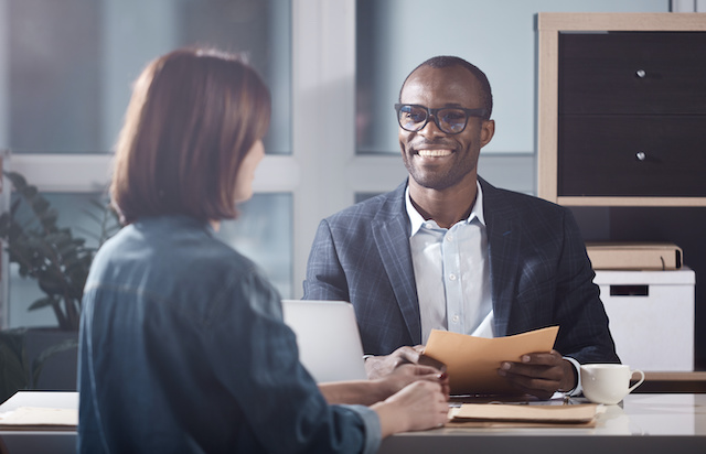 A smiling male manager interviews a female job candidate.