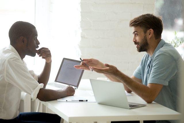 A bearded male manager defines expectations for his African American male employee during his performance review