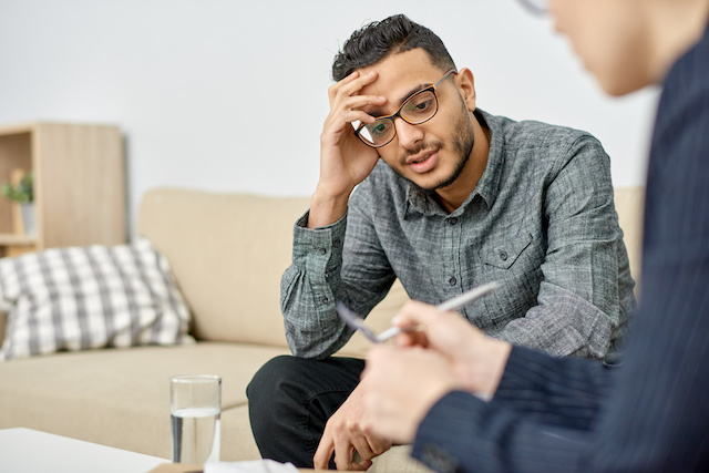 A young man sits in therapy opposite his therapist