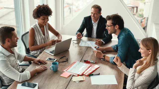 A diverse group of colleagues meet to review their company's benefits.