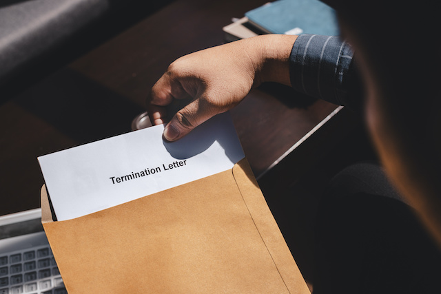 A man pulls a termination letter out of a manila envelope.