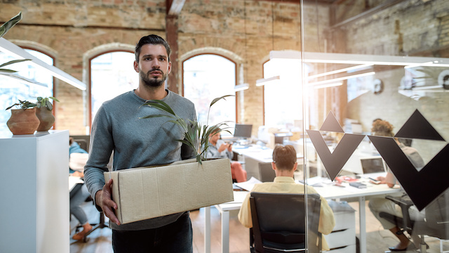 An employee leaves the office with a box of his belongings.