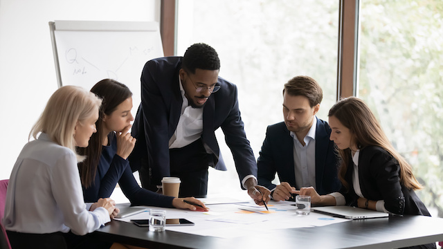 A Black male director with strong change leadership skills helps his team strategize at a meeting.