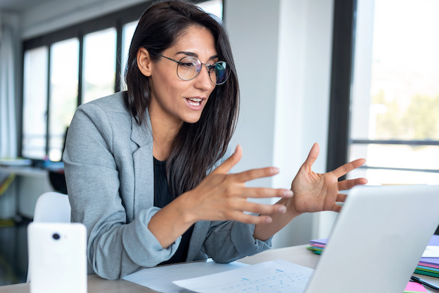 A female career coach wearing glasses gestures while offering guidance in a remote session with an employee.