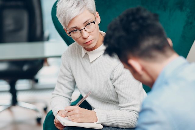 A female manager checks in with a remaining employee following layoffs.