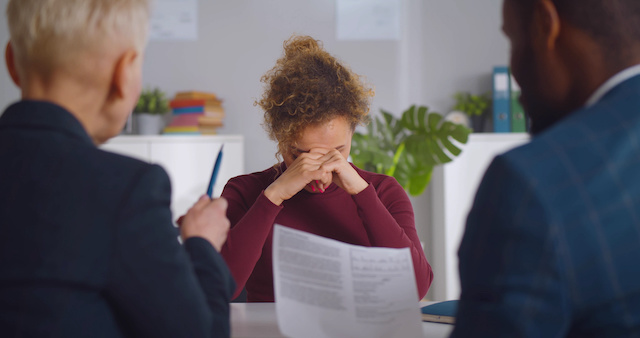 An HR manager and team leader meet with an upset female employee to fire her.