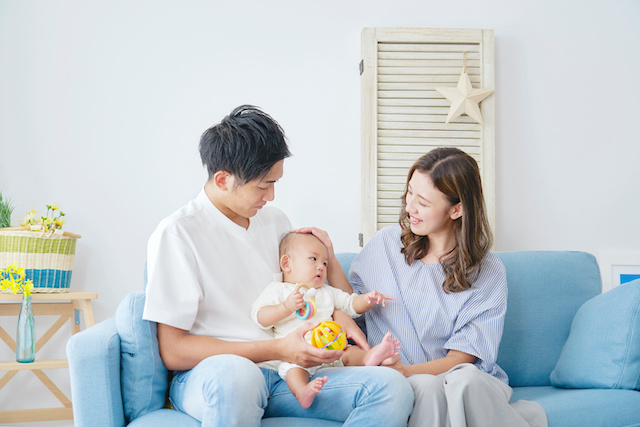 Asian parents with their newborn sitting on a light blue sofa