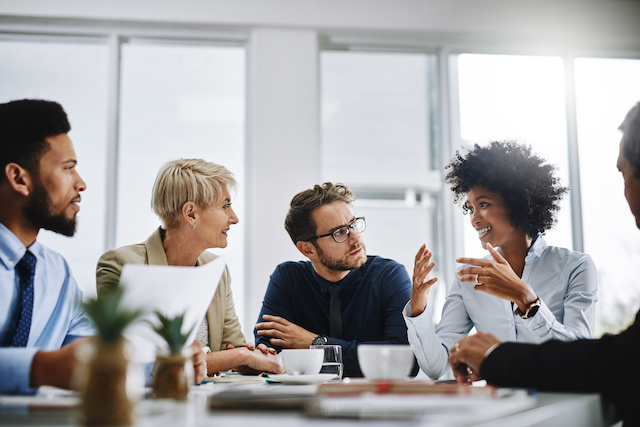 A team of coworkers meet with an employee who has moved into a new position after hers was eliminated