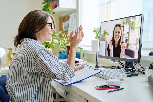 A female career coach wearing glasses helps a young woman remotely.