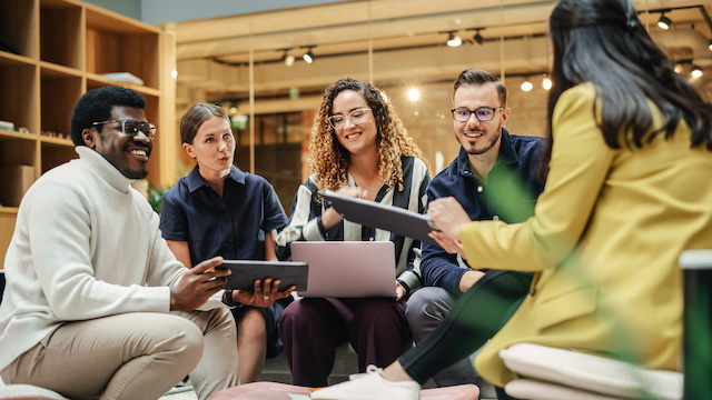 A diverse group of colleagues meet in a casual sitting area to work on a project