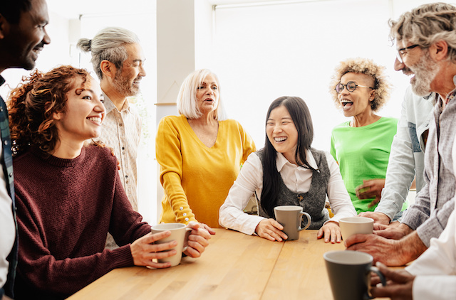 A diverse group of colleagues gather for coffee and laughter