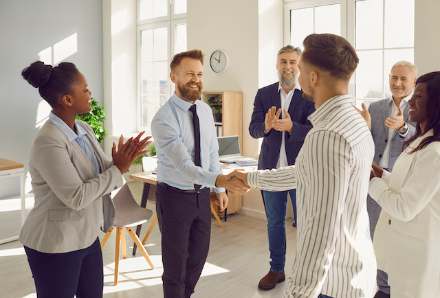 A team of diverse employees celebrates the achievements of their male colleague