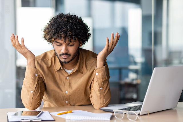 A male employee frustrated by his colleagues' quiet quitting puts his hand in the air