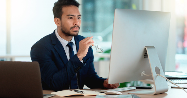 A male manager analyzes work on his computer