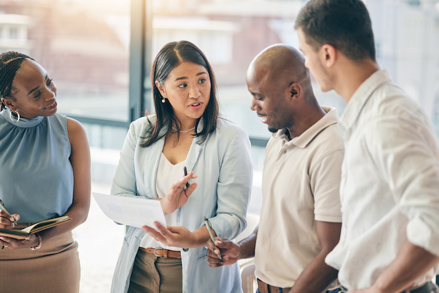 A female manager reviews priorities with three employees