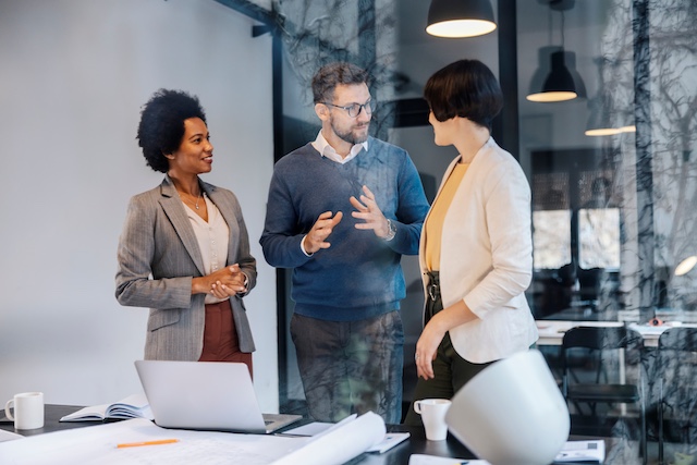 A male leadership coach speaks with two female leaders