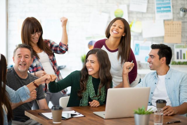 A team of creative employees celebrate the completion of a project