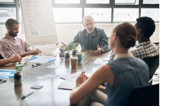 Employees meet to work on a challenging project to boost their leadership skills