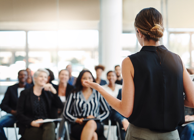 A female employee confidently addresses her colleagues during a presentation