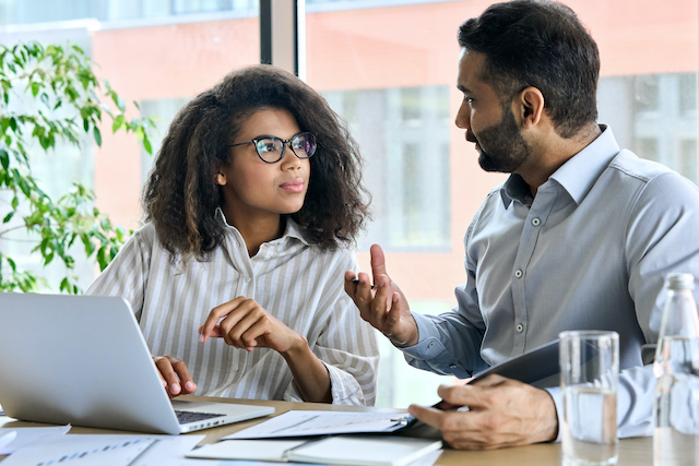 A male, bearded manager meets with his female employee