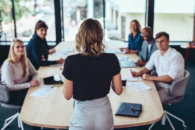 A female employee with strong communication skills presents to her colleagues.