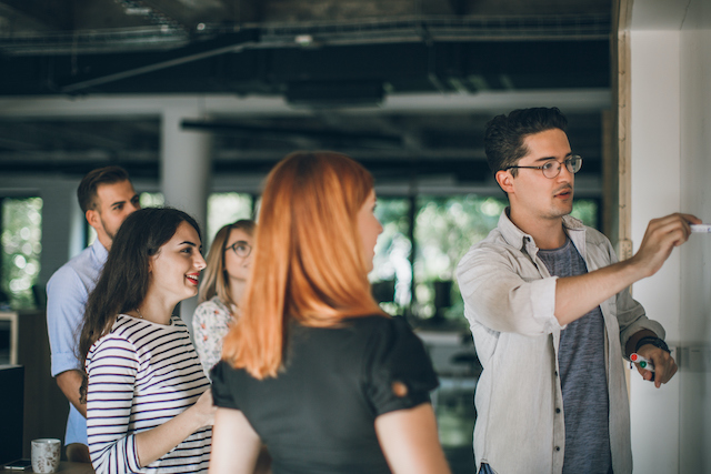 A young male employee leads a project team in a brainstorm.