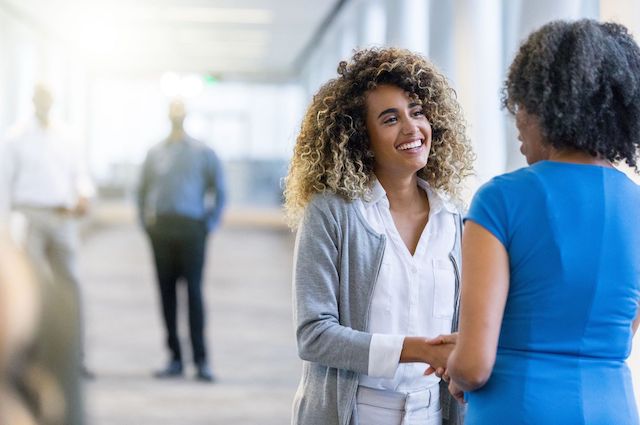 A Black female hiring manager welcomes a new Black female employee.