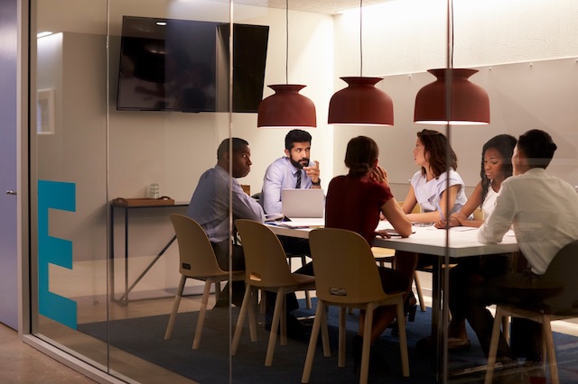 A manager communicating layoffs to his remaining employees in a meeting