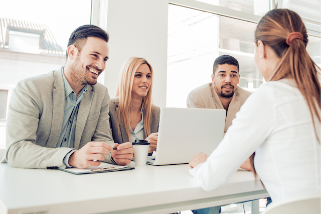 Two men and a woman interview a female candidate for a job.