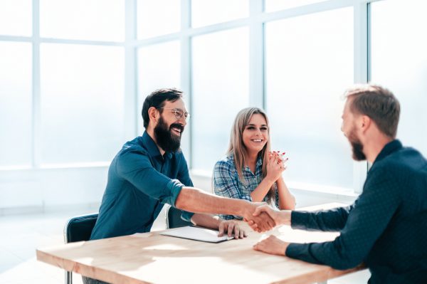 A male senior manager joins a female hiring manager to interview a male candidate.